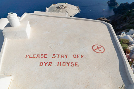 Oia, Santorini, Greece - 22 July 2014: Sign on a roof of a Greek house saying 'Please stay off our house' to avoid tourists stepping onのeditorial素材
