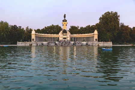 Boats at the lake at the park of Buen Retiro with monument of Alfonso XII King of Spain at sunset, Madrid, Spainの写真素材