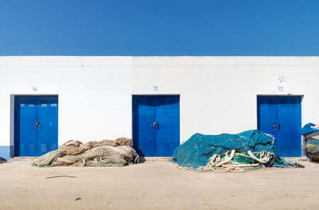 White harbour warehouse building with blue doors and fisher nets and cloudless blue sky, Altea, Costa Blanca, Spainの写真素材