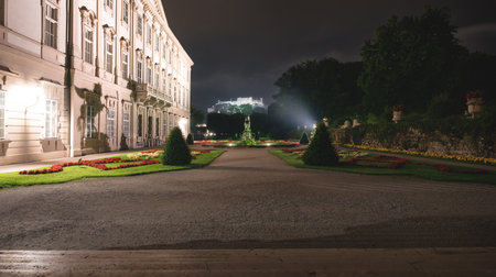 Salzburg, Austria - 2 August 2020: Lightened baroque Mirabell park with colorful flowers and palace in the night with view on castle Hohensalzburgのeditorial素材