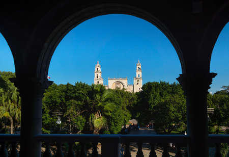 View through arches to the cathedral of Merida over the main square park 'Plaza Grande' from the Olimpo Cultural Center in Merida, Yucatan, Mexicoの写真素材
