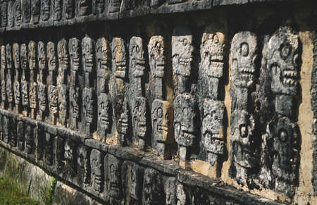 Wall with carved skulls in a stone Mayan temple in Chichen Itza, Yucatan, Mexico