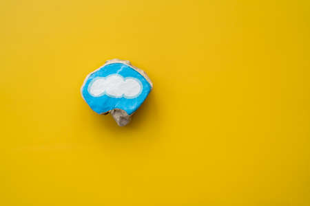 Painted stone with blue bordered cloud on yellow background as symbol for handcraft hobby and...