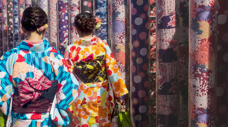 Kyoto, Japan - September 18, 2017: Woman in traditional dress visiting kimono forest with poles decorated with kimono fabrics in the kyoyuzen style at Arashiyama Stationのeditorial素材