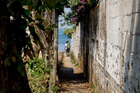 San Pedro la Laguna, Guatemala - March 27, 2018: Local man with cowboy hat walking down a small path between trees and walls to the lake Atitlanのeditorial素材