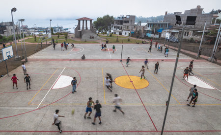 Santiago Atitlan, Guatemala - March 29, 2018: Local men playing football and basketball on the concrete sports field along the lake in Santiago Atitlan, Guatemalaのeditorial素材
