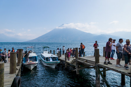 San Marcos la Laguna, Guatemala - March 29, 2018: People boarding and arriving with motor boats at the jetty with view on volcanoのeditorial素材