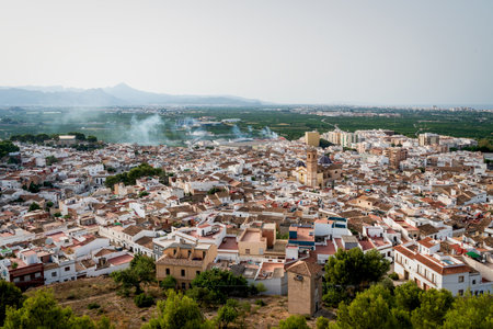 Aerial view from the castle 'Santa Anna' on the Spanish old town with the church tower and blue tiled domes of 'San Roque' in the center, Oliva, Spainのeditorial素材