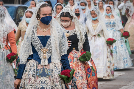 Valencia, Spain - 4 September 2021: Women with face masks for covid protection and traditional floral dresses walking for the parade at the celebration 'Fallas'のeditorial素材