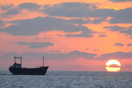 Cargo ship passing the setting sun off the coast of Cyprus