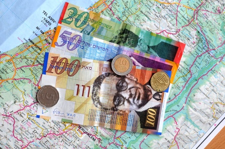 paper money and coins on the map of israel
