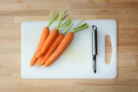 details of carrots on a cutting board with a peelerの写真素材