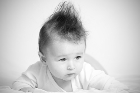Portrait of a baby 4 months old lying on his belly with mohawk hairstyle.の写真素材