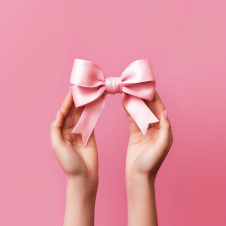 Generative AI : First person top view photo of valentines day decorations young womans hands holding heart shaped giftbox with pink ribbon bow on isolated pastel pink backgroundの素材