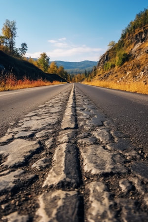 Generative AI : Empty dirt road amidst autumn trees in front of blue skyの素材