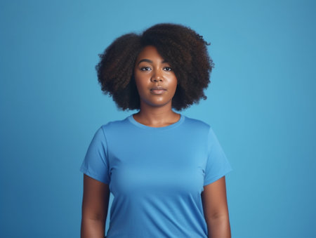 Charming girl Attractive young African woman looking at camera while standing against blue background : Generative AIの素材