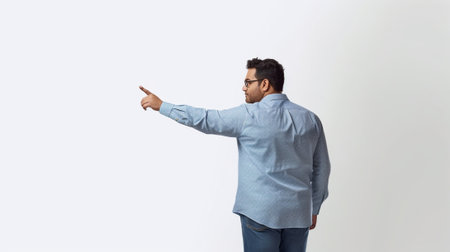 Businessman pointing copy space Handsome young man in shirt looking at camera and pointing away while standing against white background : Generative AIの素材