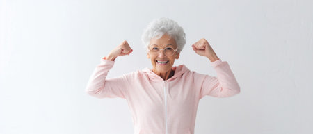 Feeling young and healthy Cheerful senior woman checking her biceps and smiling while standing isolated on white background : Generative AIの素材