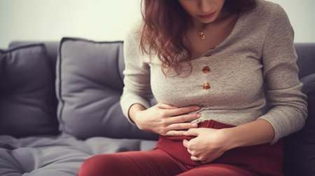 In pain Young sad woman suffering from the stomachache while sitting on the sofa at home : Generative AIの素材