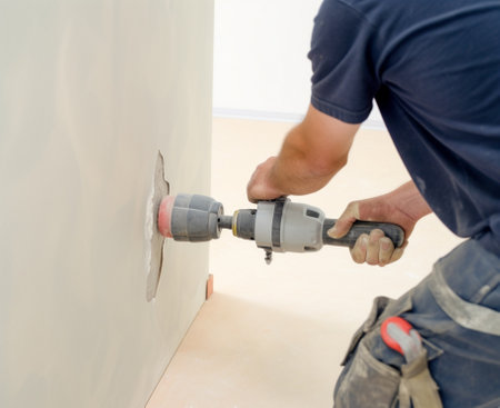 Hammer concrete with a hammer drill to make a hole for heating pipes Tools of plumber for clamps the connectors on the pipe connection heating pipes to white Radiator in  : Generative AIの素材