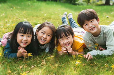 Four cute barefooted kids in summer clothes laying on green grass with black laptopCopy space : Generative AIの素材