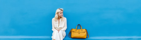 Stay at home and be safe Serious blonde fifty years old woman wears protective mask on face avoids social contact poses alone near empty chair against blue wall Pandemic  : Generative AIの素材