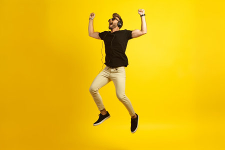 Pleased african man with sincere smile dancing on yellow background Studio photo of enthusiastic blackhaired guy wears white sneakers : Generative AIの素材