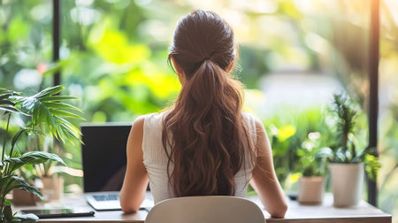 Back view of young businesswoman working with laptop computer at home office.の素材