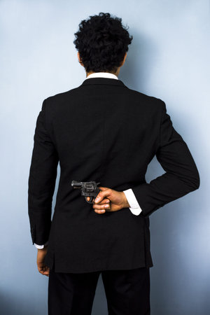 Businessman hiding gun behind his backの写真素材