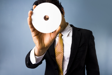 Businessman looking through a blank DVDの写真素材