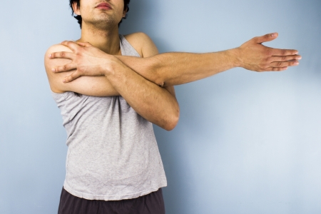 Young multiracial man stretching his shoulderの写真素材