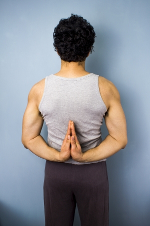 Rear view of young man in yoga pose with hands togetherの写真素材