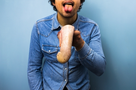Man messing around with a raw beef tongueの写真素材