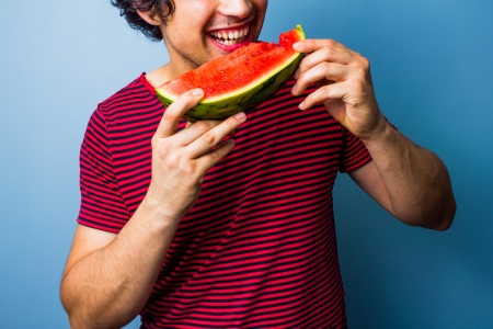 Young man eating water melonの写真素材