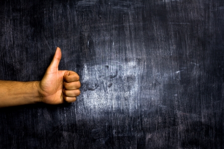 Man giving thumbs up on blackboard backgroundの写真素材