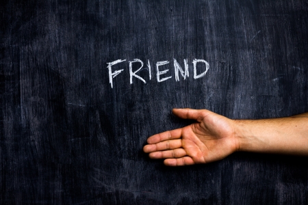 Shaking hands with the word friend written on blackboardの写真素材