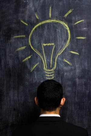 Businessman at blackboard having bright ideaの写真素材