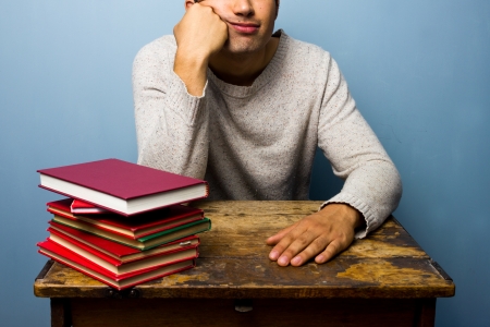 Bored man at desk with booksの写真素材
