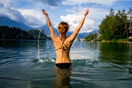 Healthy young woman splashing around in a mountain lakeの写真素材