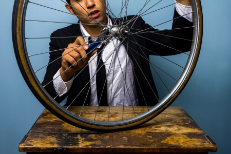 Young businessman is trying to fix a bicycle tyreの写真素材