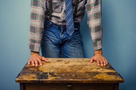 Young man in trendy clothing is leaning on an old deskの写真素材