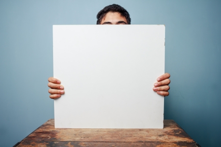 Man holding white board at deskの写真素材