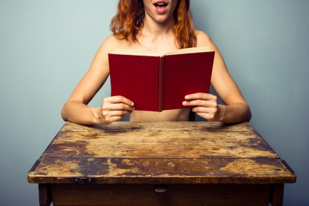 Naked woman hiding behind a bookの写真素材