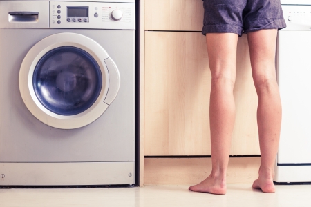 Woman s bare legs in kitchen by washing machineの写真素材