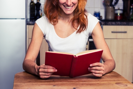 Happy young woman is reading in her kitchenの写真素材