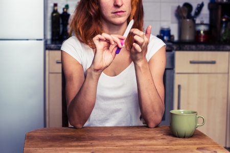 Woman is filing her nails in her kitchenの写真素材