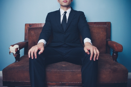 Young businessman is sitting on sofa in a powerful poseの写真素材