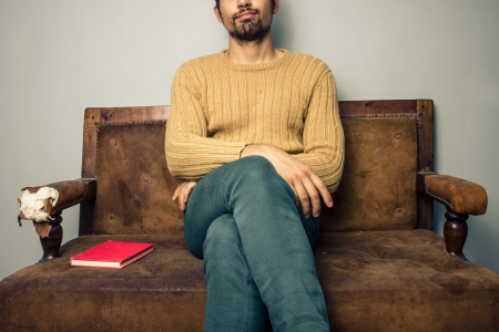 Young man is sitting on a vintage sofaの写真素材