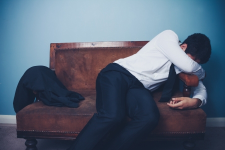 Tired young businessman relaxing on a vintage sofaの写真素材