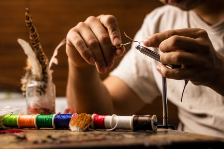 Young man tying flies for fly fishingの写真素材